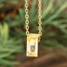 Yellow gold cremains urn necklace on a blurred background