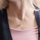 Yellow gold cremains urn necklace worn by a person