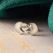 Silver crescent moon earrings on a wooden surface with green fabric in the background
