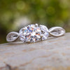 Diamond center stone ring with leaf accents on a natural background