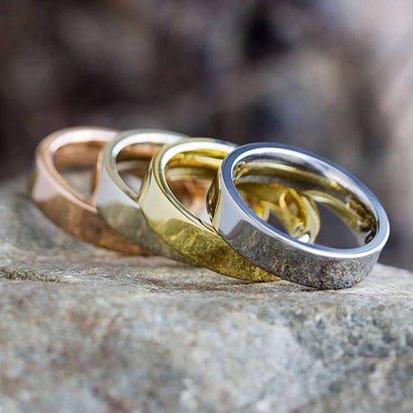 Four rings of different metal types on a rock