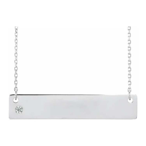 Silver necklace with a bar pendant and small round gemstone on a white background