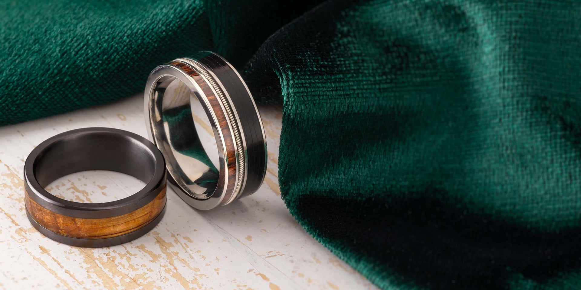 Two Custom Men's Rings from Jewelry by Johan on a wooden surface