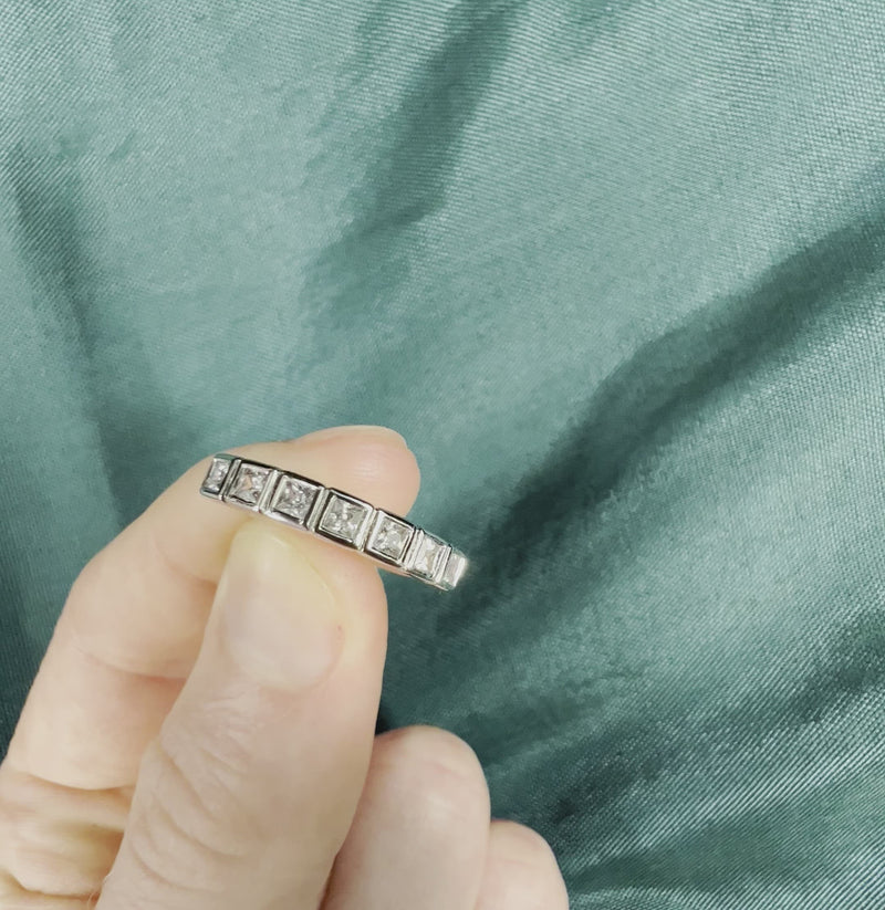 Hand holding square cut diamond anniversary band with bezel setting