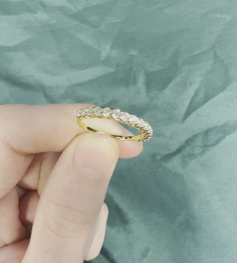 Hand holding diamond wedding band with shared prong design