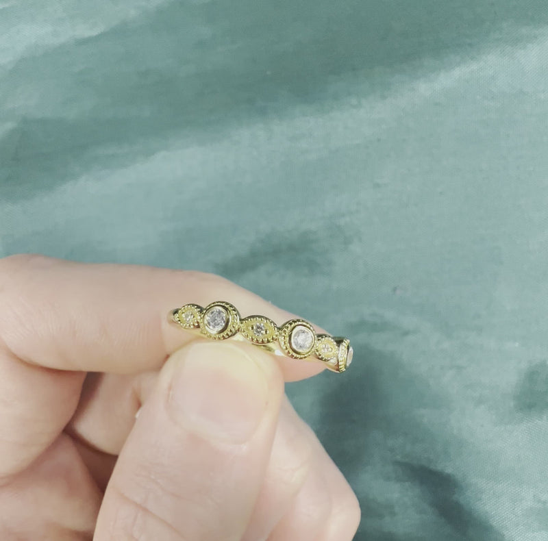 Hand holding vintage style diamond band with bezel settings