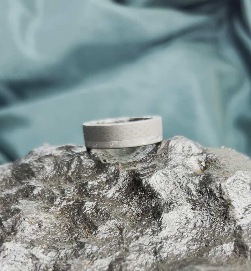 Meteorite ring with Celtic design on rocky surface