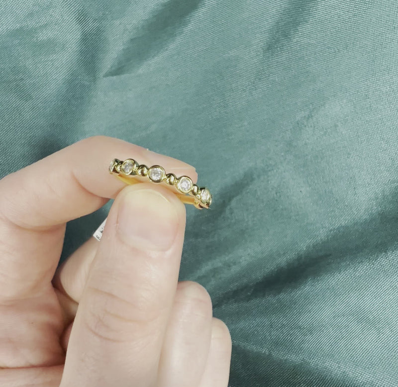 Hand holding bezel set diamond and gold ball ring