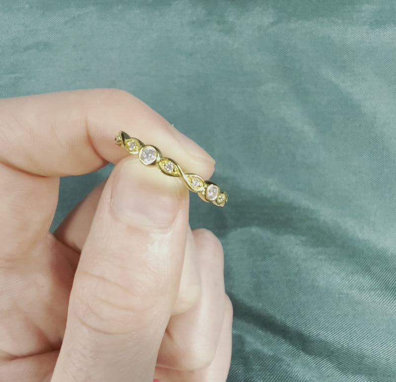 Hand holding gold ring with diamond infinity pattern