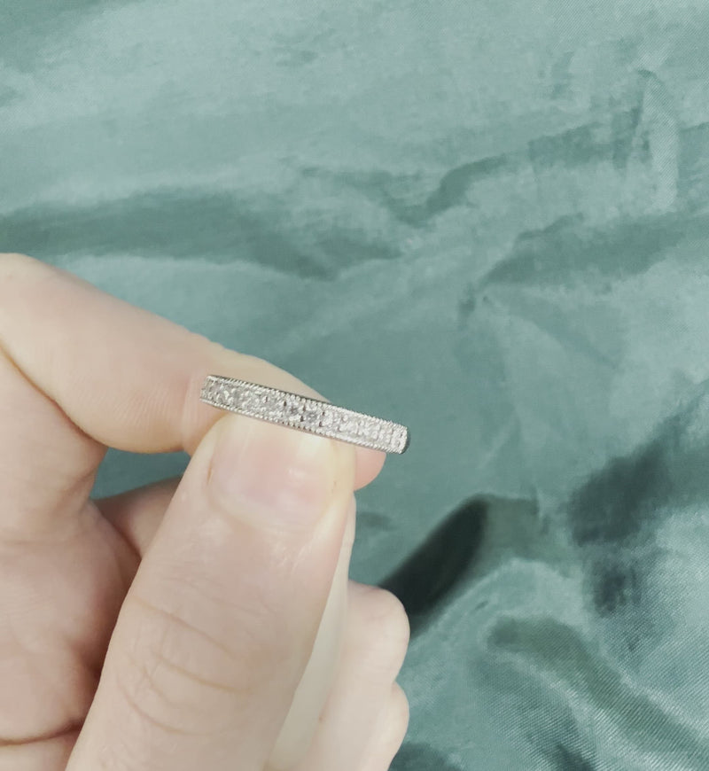 Hand holding diamond anniversary band with milgrain edges