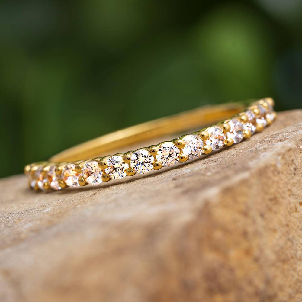 Yellow gold diamond anniversary band on stone surface