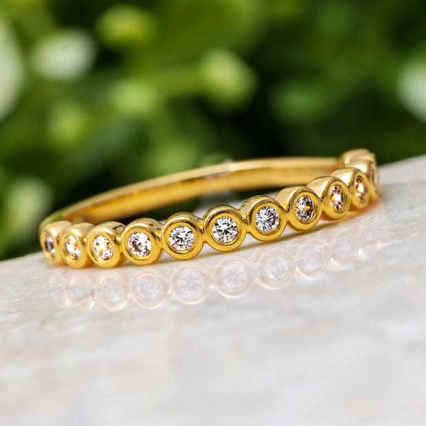 Yellow gold bezel set diamond anniversary band on marble