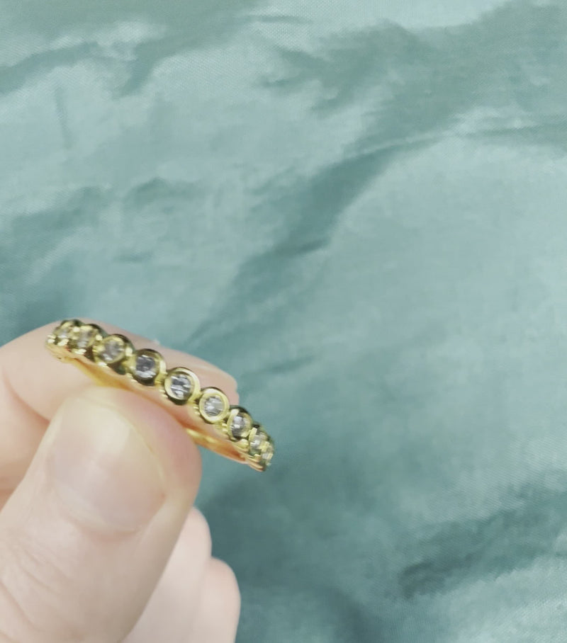 Hand holding yellow gold bezel set diamond anniversary band