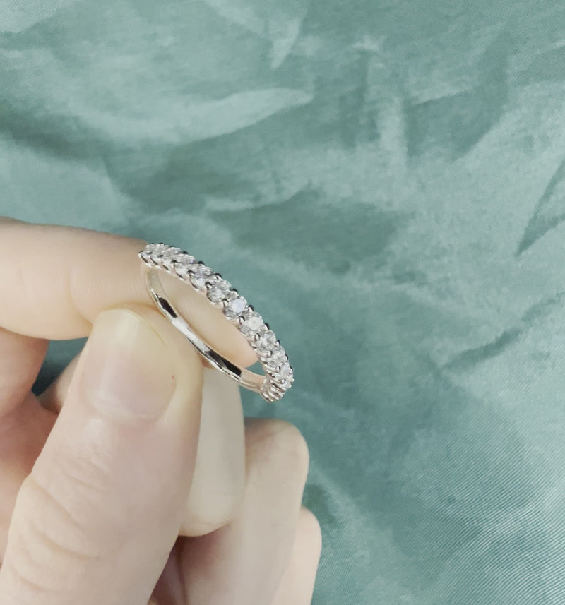 Hand holding diamond anniversary band with prong setting