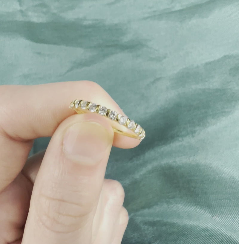 Hand holding yellow gold eternity band with diamonds